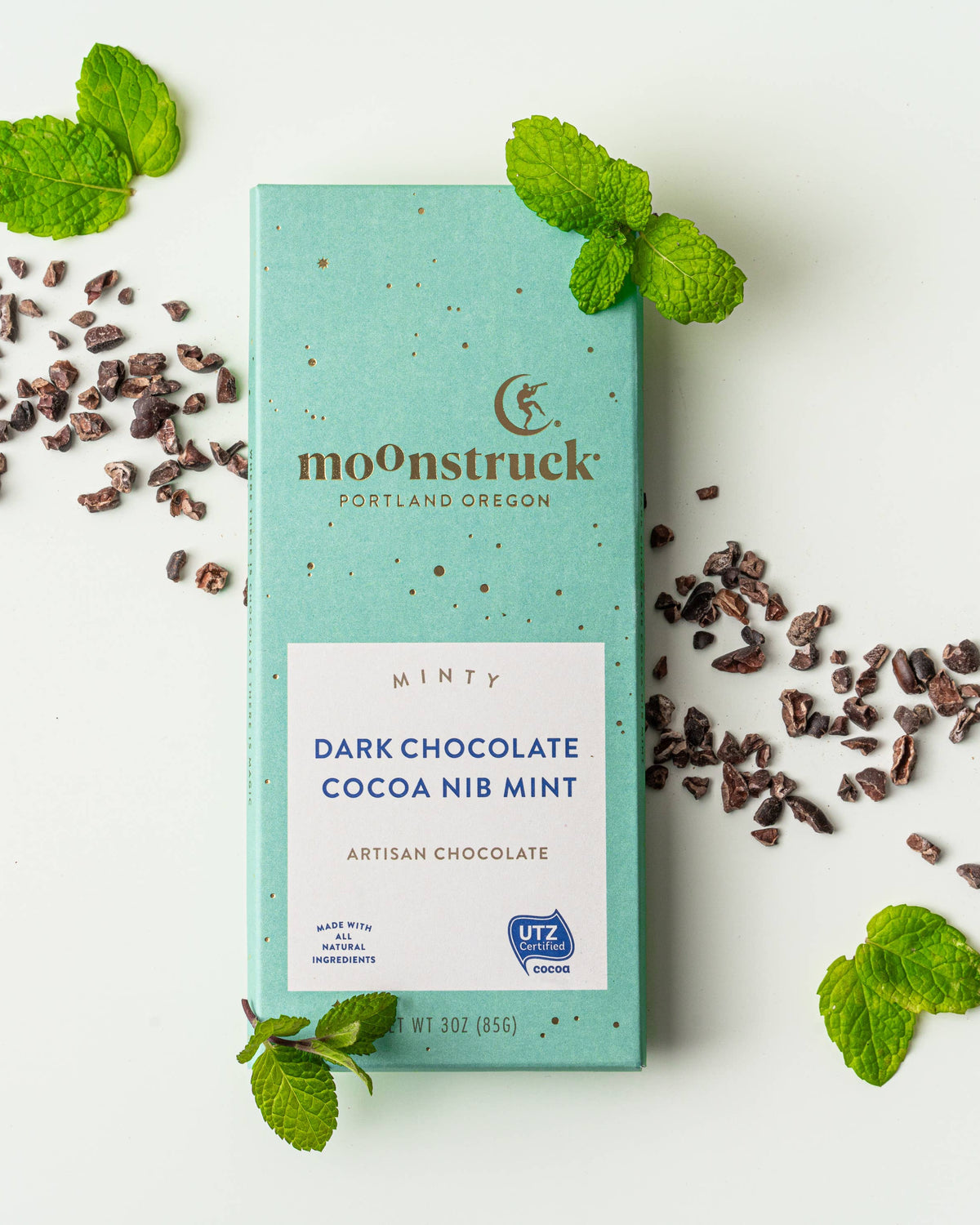 Mint chocolate bar with cocoa nibs and mint leaves on a white background
