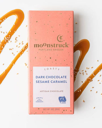 Moonstruck dark chocolate sesame caramel bar packaging on a white background with caramel drizzle.