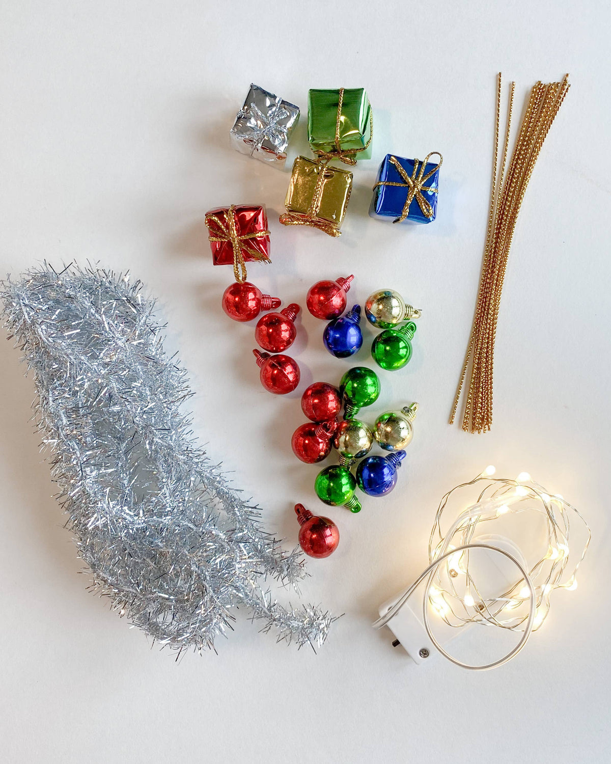 Christmas decorations including tinsel, ornaments, and lights on a white background