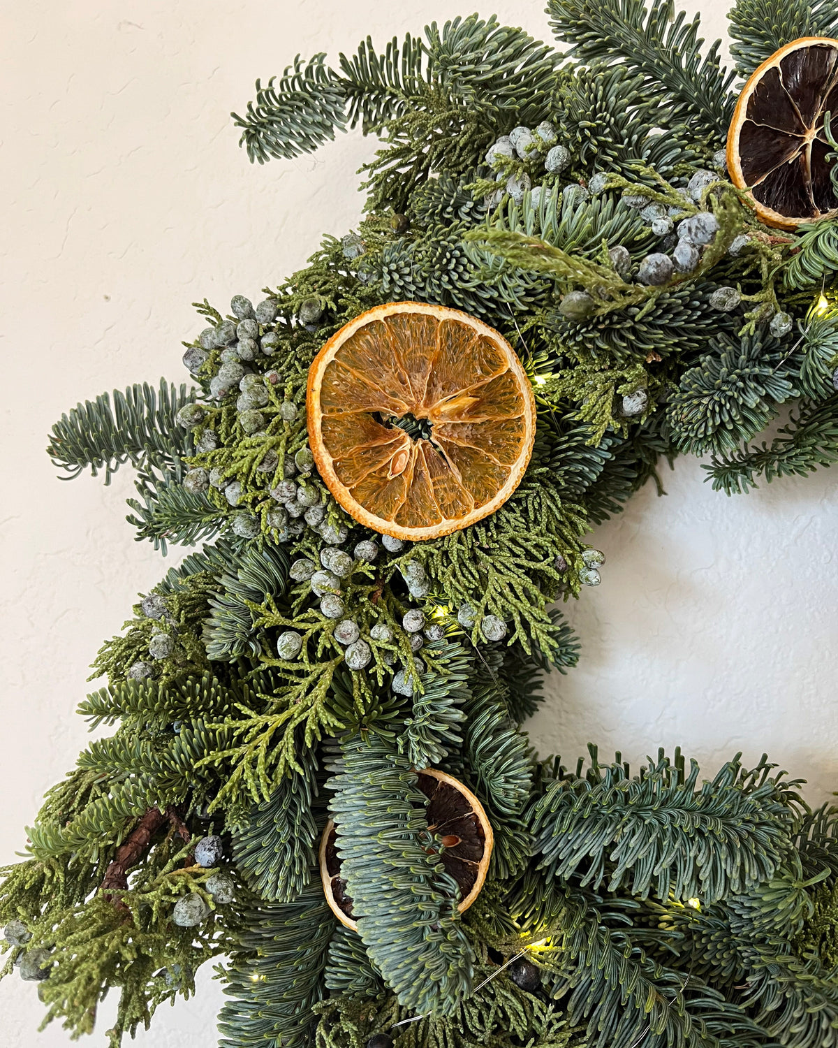 Christmas wreath with greenery and dried orange slices on a light background