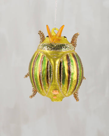 Decorative beetle ornament with gold accents on a plain background