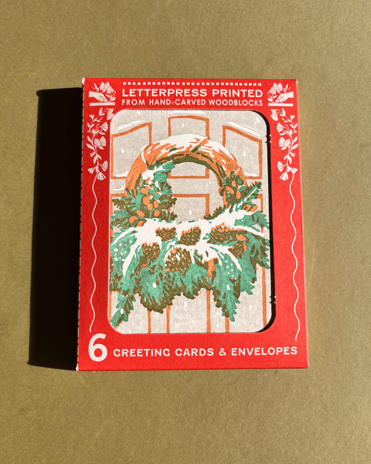 Pack of greeting cards with a wreath design on a beige background