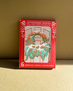 Box of letterpress printed greeting cards with a wreath design on a beige background