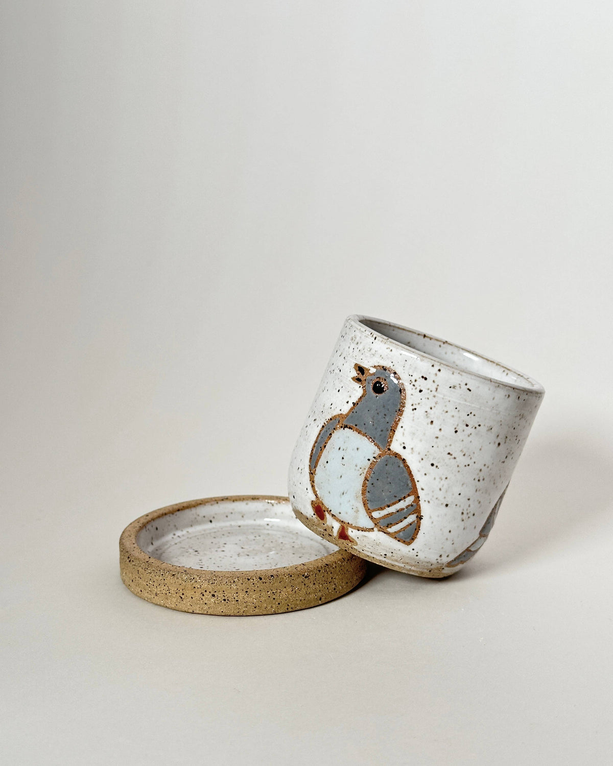 Ceramic container with a bird design on a light gray background