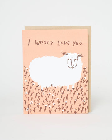 Greeting card with a sheep illustration and 'I woolly love you' text on a pink background