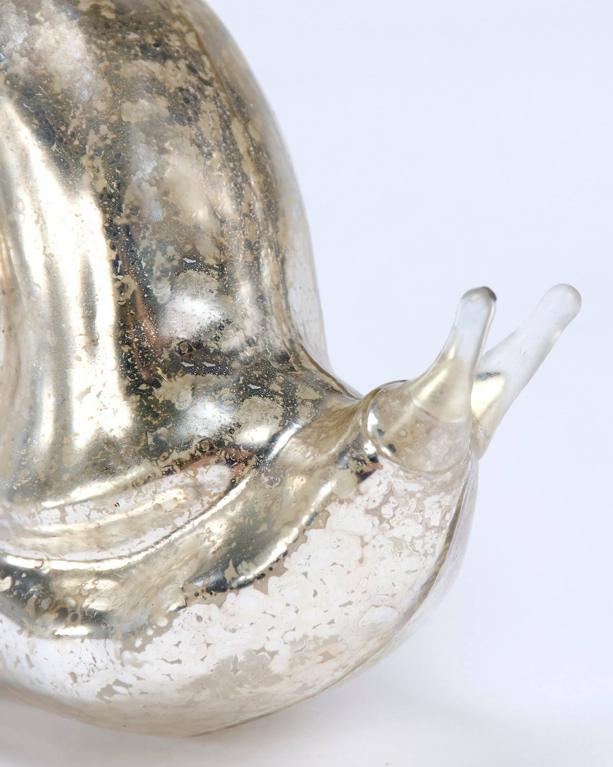 Close up of a metallic snail ornament on a white background