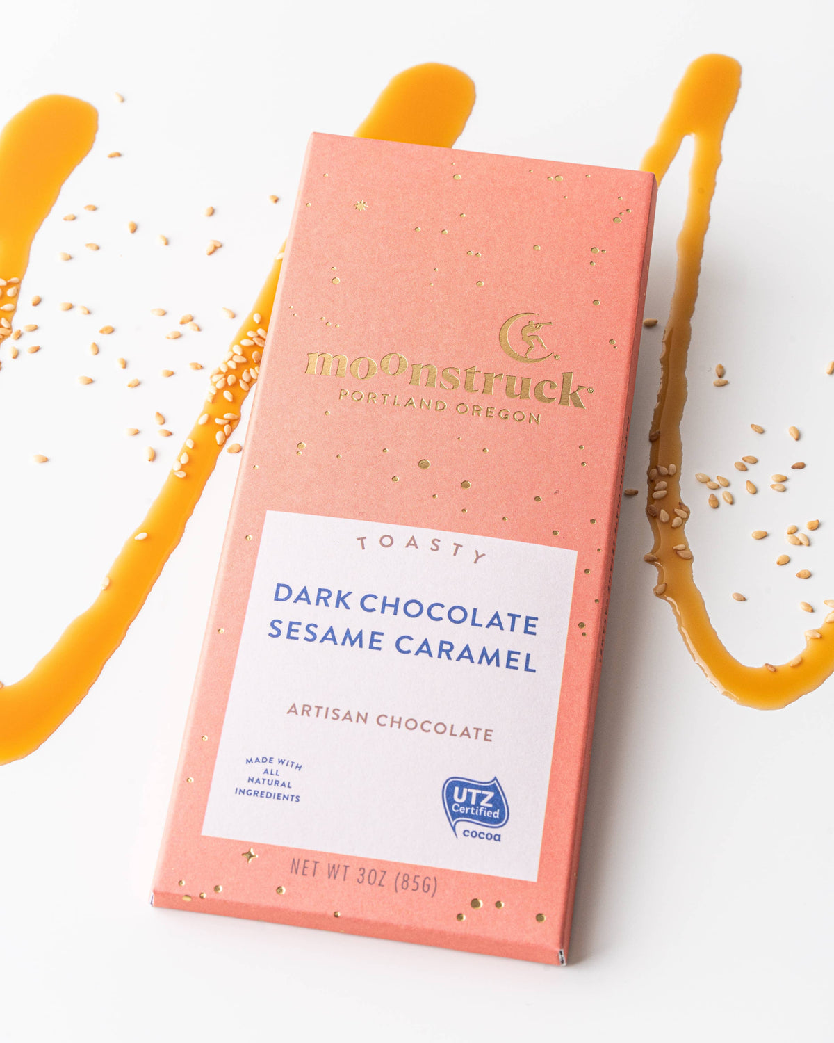 Moonstruck dark chocolate sesame caramel bar packaging on a white background with caramel drizzle.