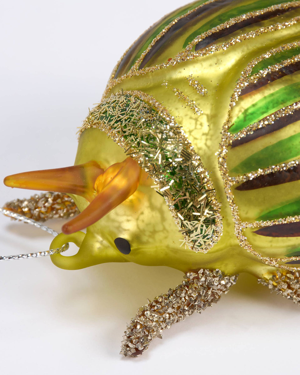 Decorative glass armadillo ornament with gold and green accents on a white background