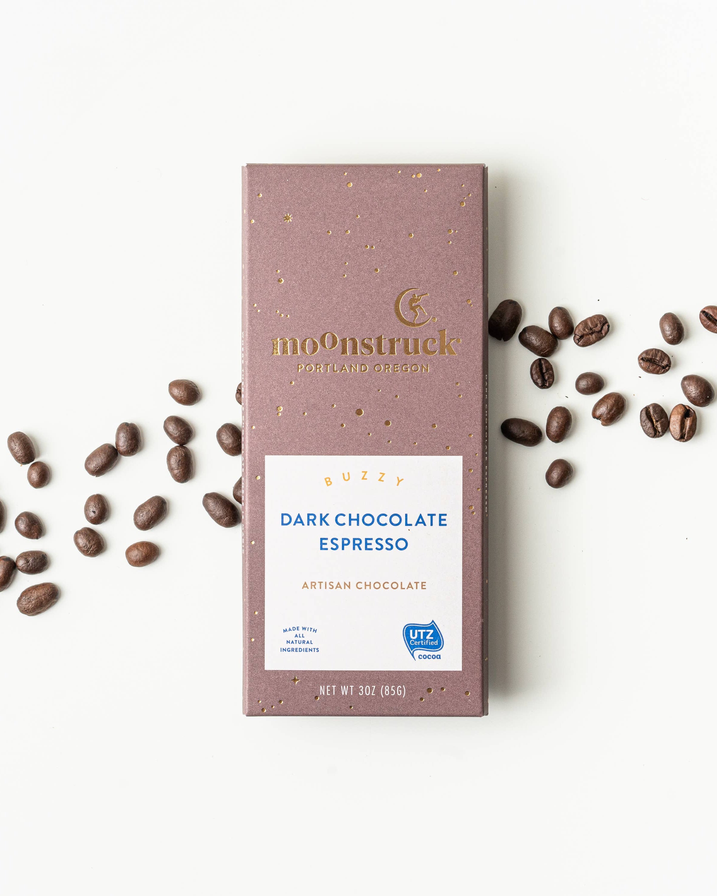 Moonstruck Dark Chocolate Espresso bar with scattered coffee beans on a white background