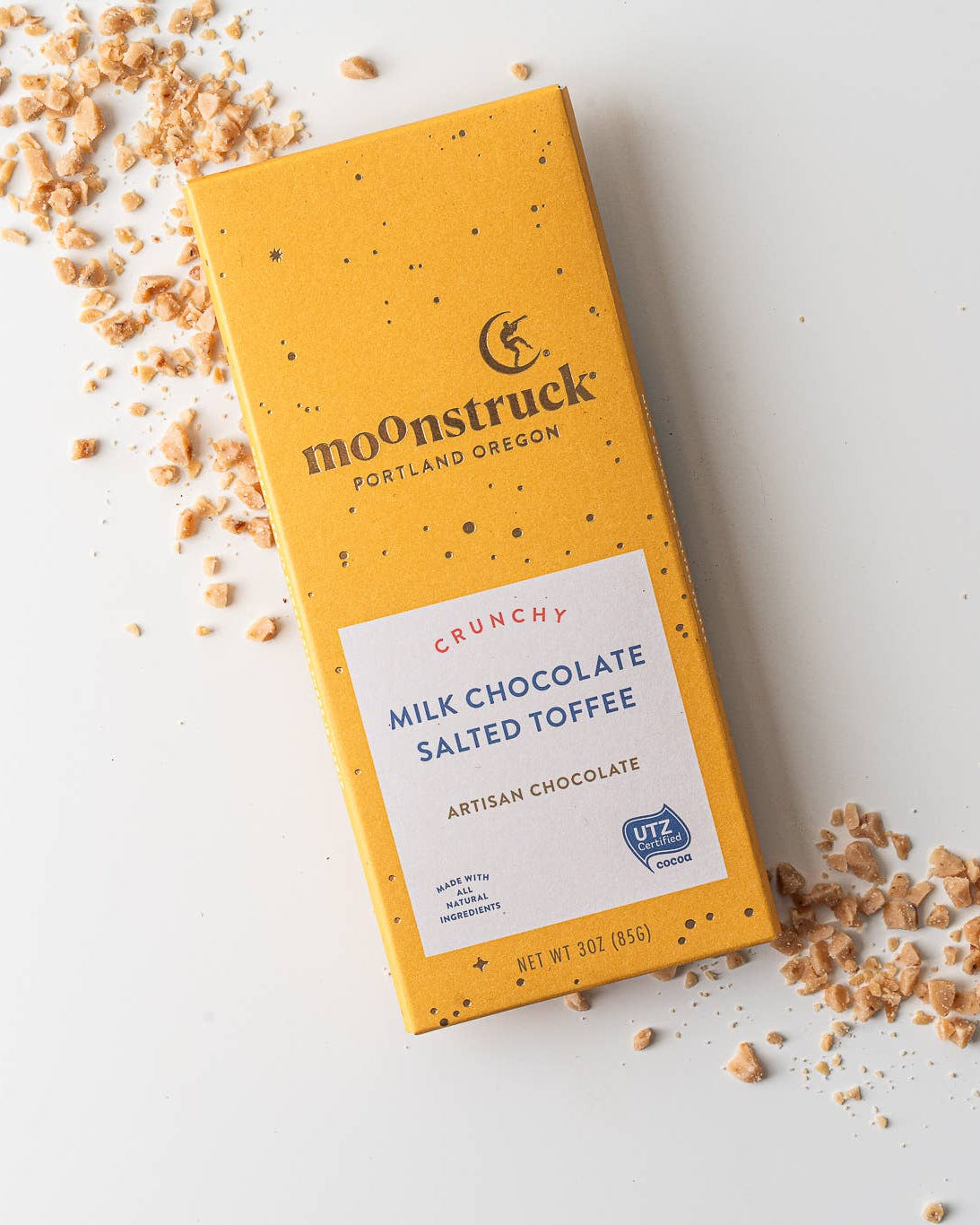 Moonstruck chocolate bar packaging with scattered toffee pieces on a light background