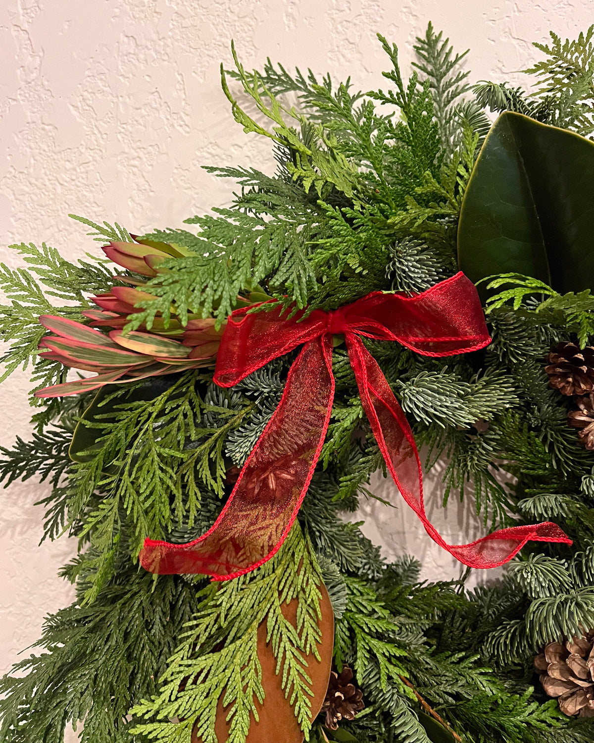 Green wreath with red ribbon on a textured wall background