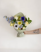 Bouquet of flowers held by a person with a tattoo on a light background
