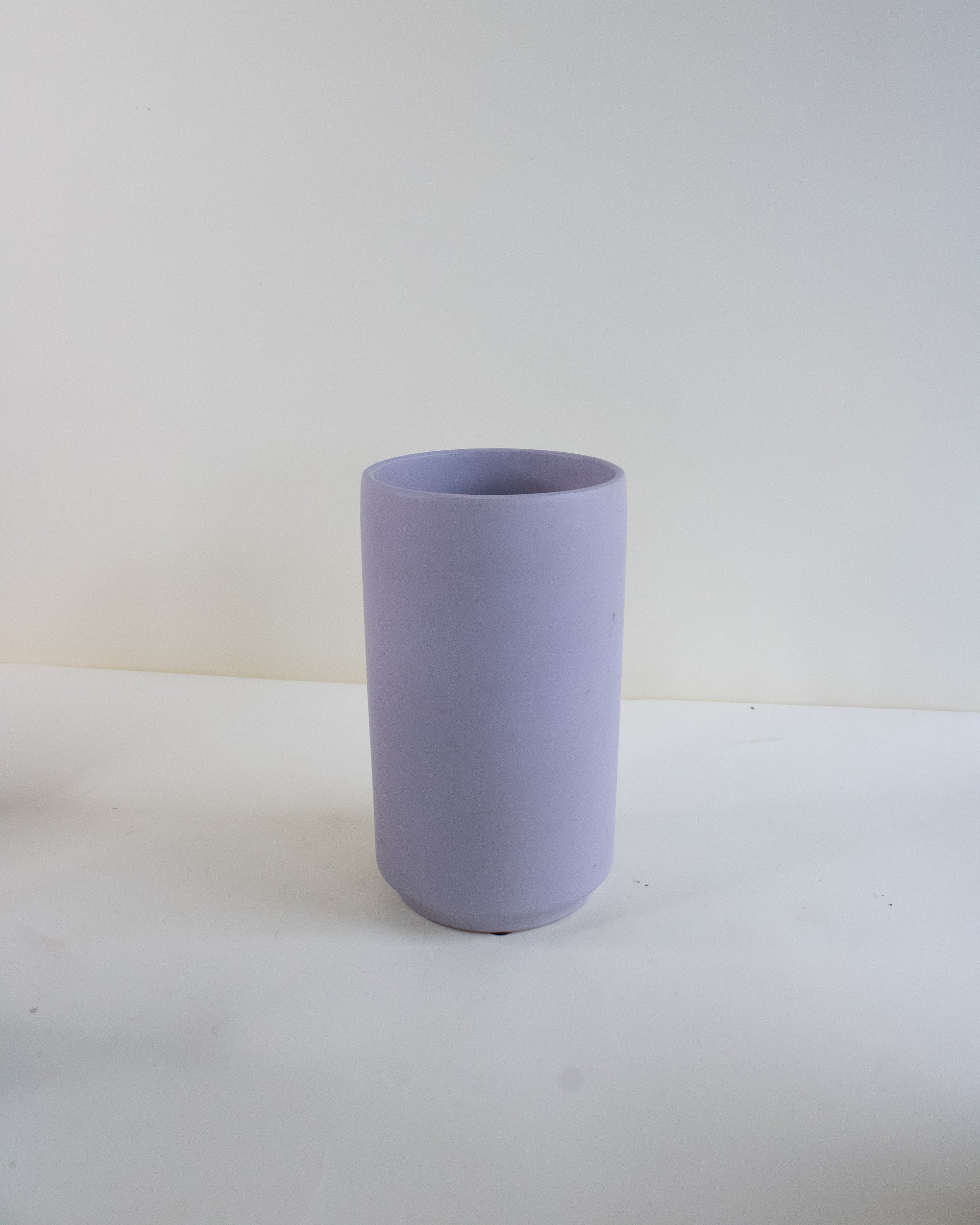 Light purple ceramic vase on a white surface with a light gray background