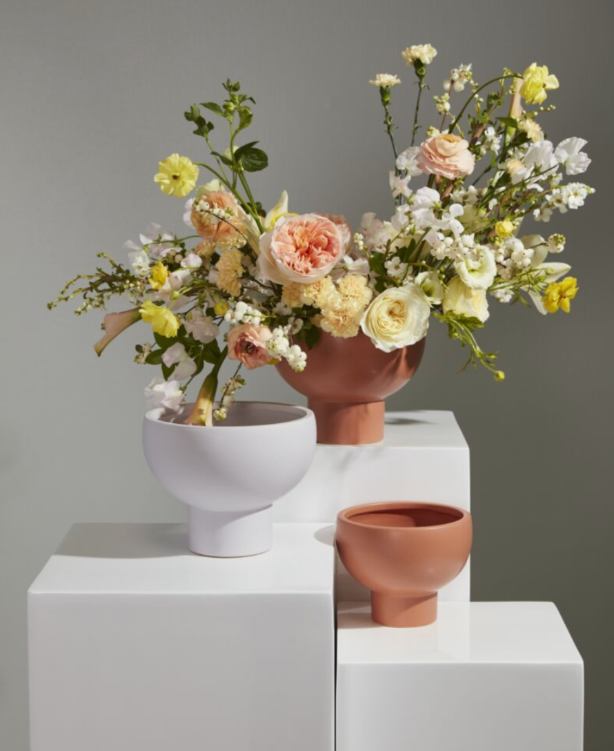 terra cotta compote with huge arc of flowers on white pedestal