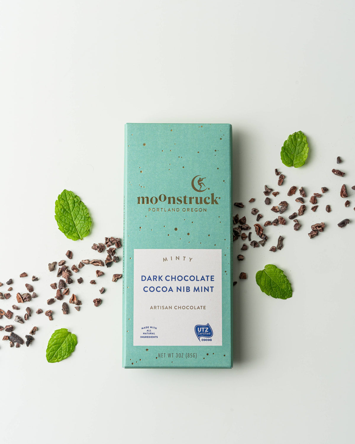 moonstruck dark chocolate cocoa nib mint bar with mint leaves on a white background