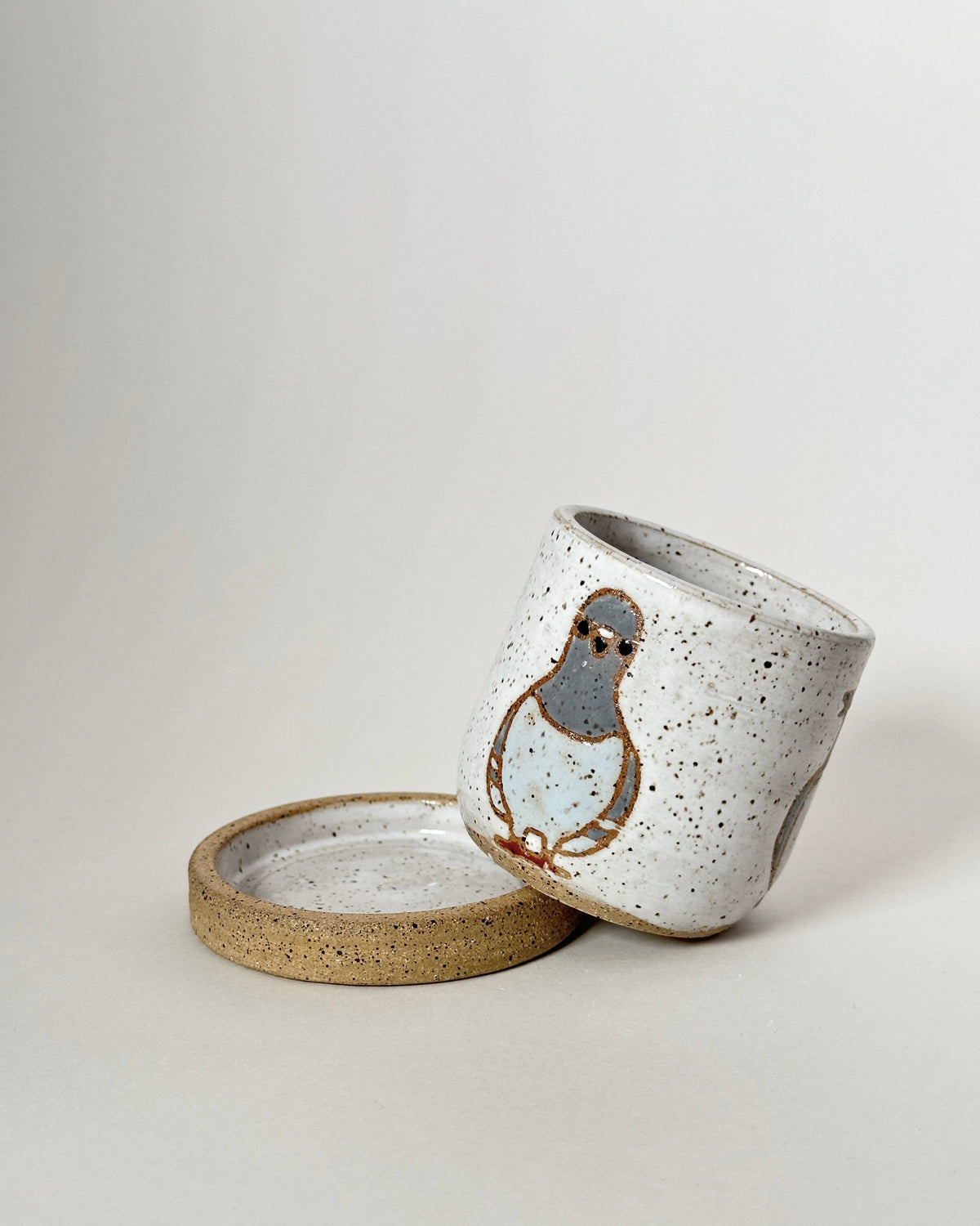 Ceramic cup with lid featuring a bird design on a light background