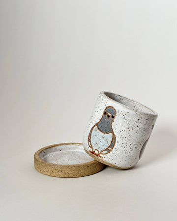 Ceramic cup with lid featuring a bird design on a light background