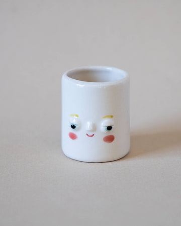 smiling tiny porcelain planter on plain backdrop