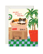 Greeting card with a cat in a box and 'Home Sweet Home' text, featuring a plant and checkered floor.