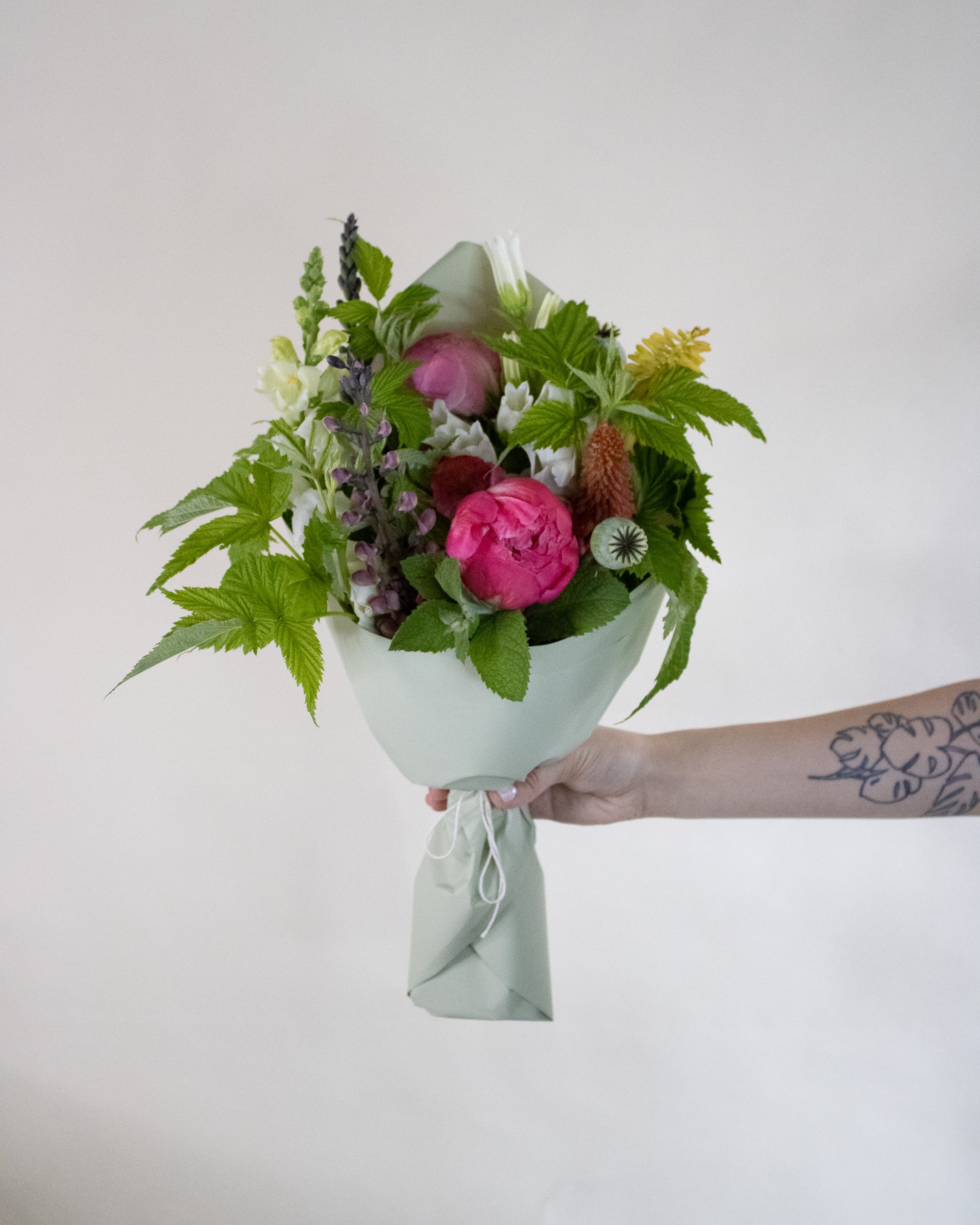 Bouquet of flowers held by a person against a plain background