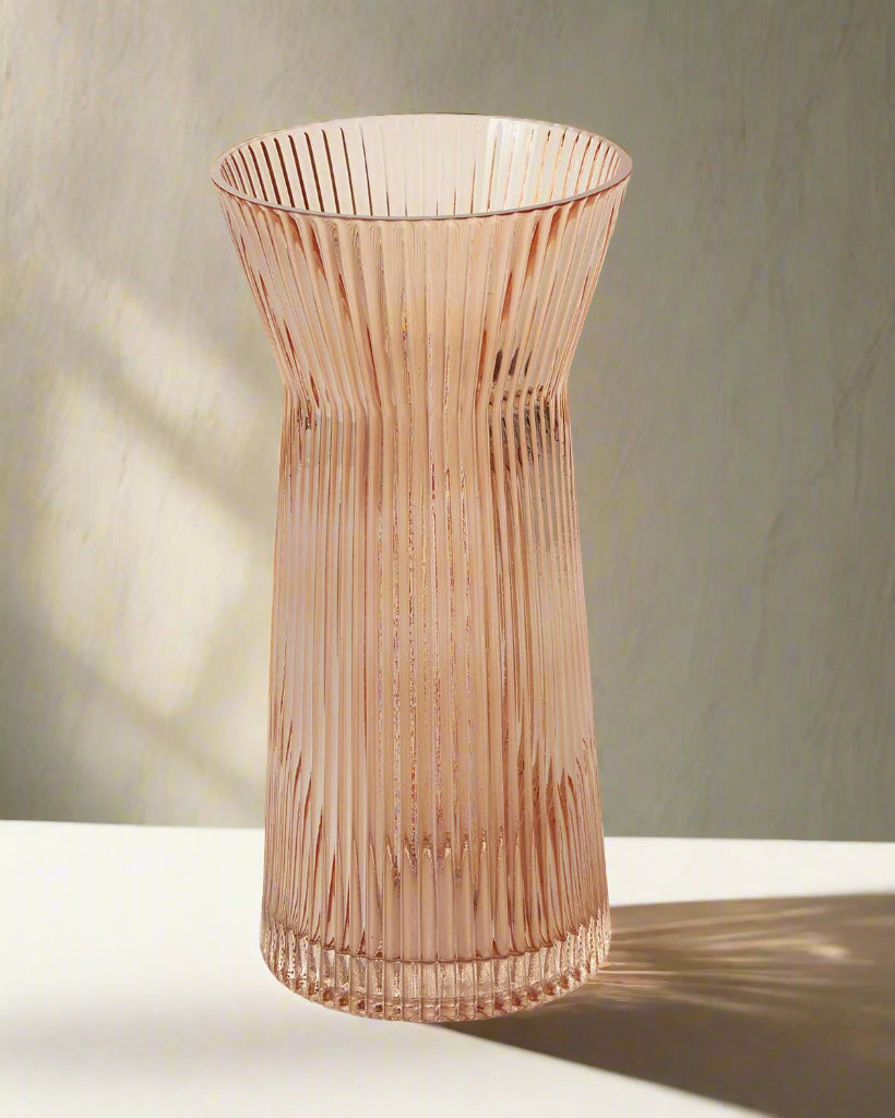 ribbed amber colored vase on table with shadows