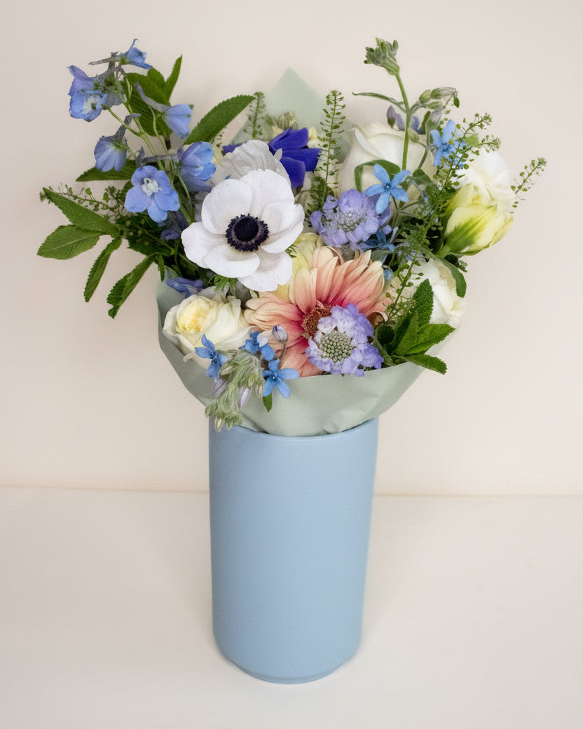 bouquet of flowers in tall light blue vase
