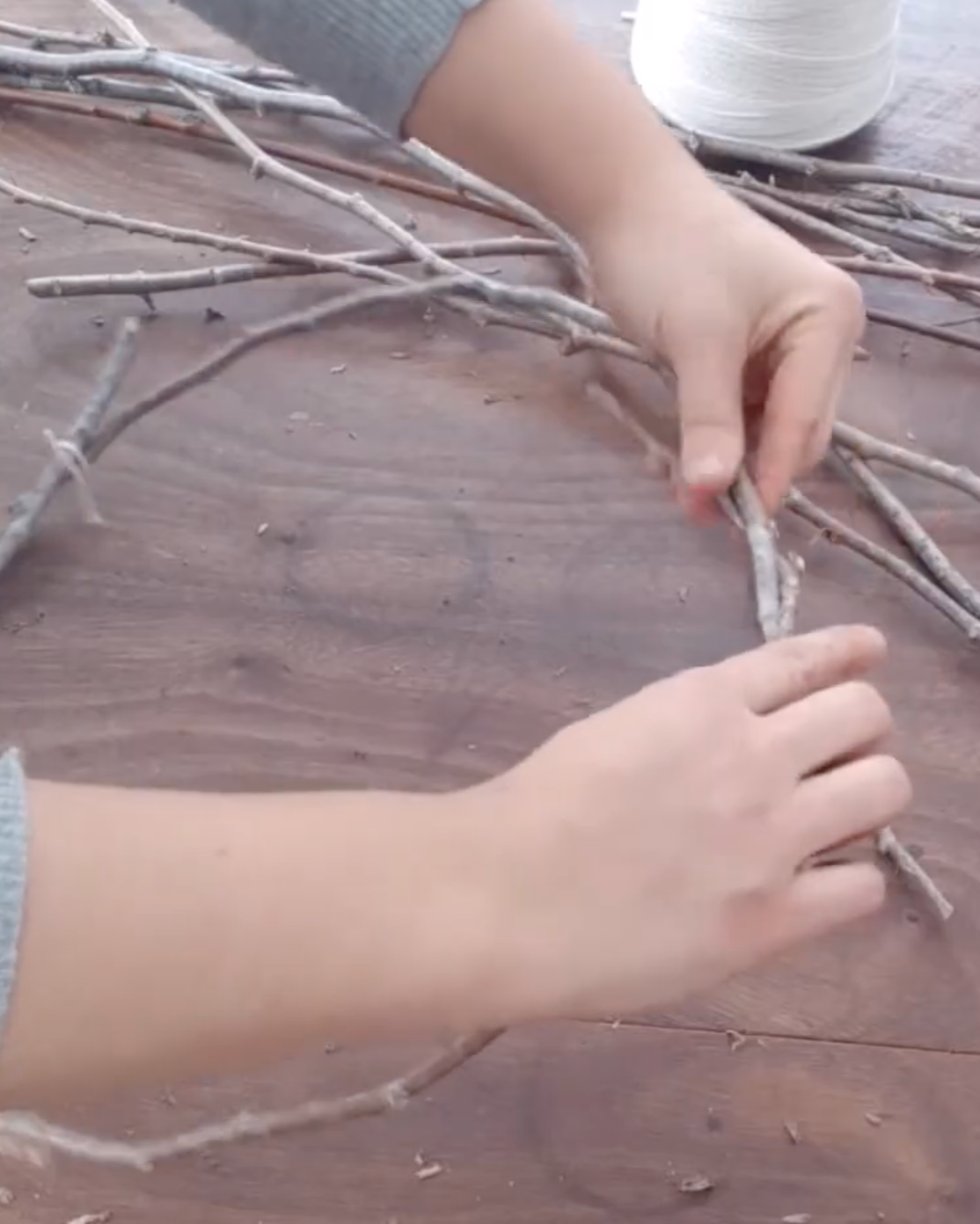 hands holding a wreath made from branches