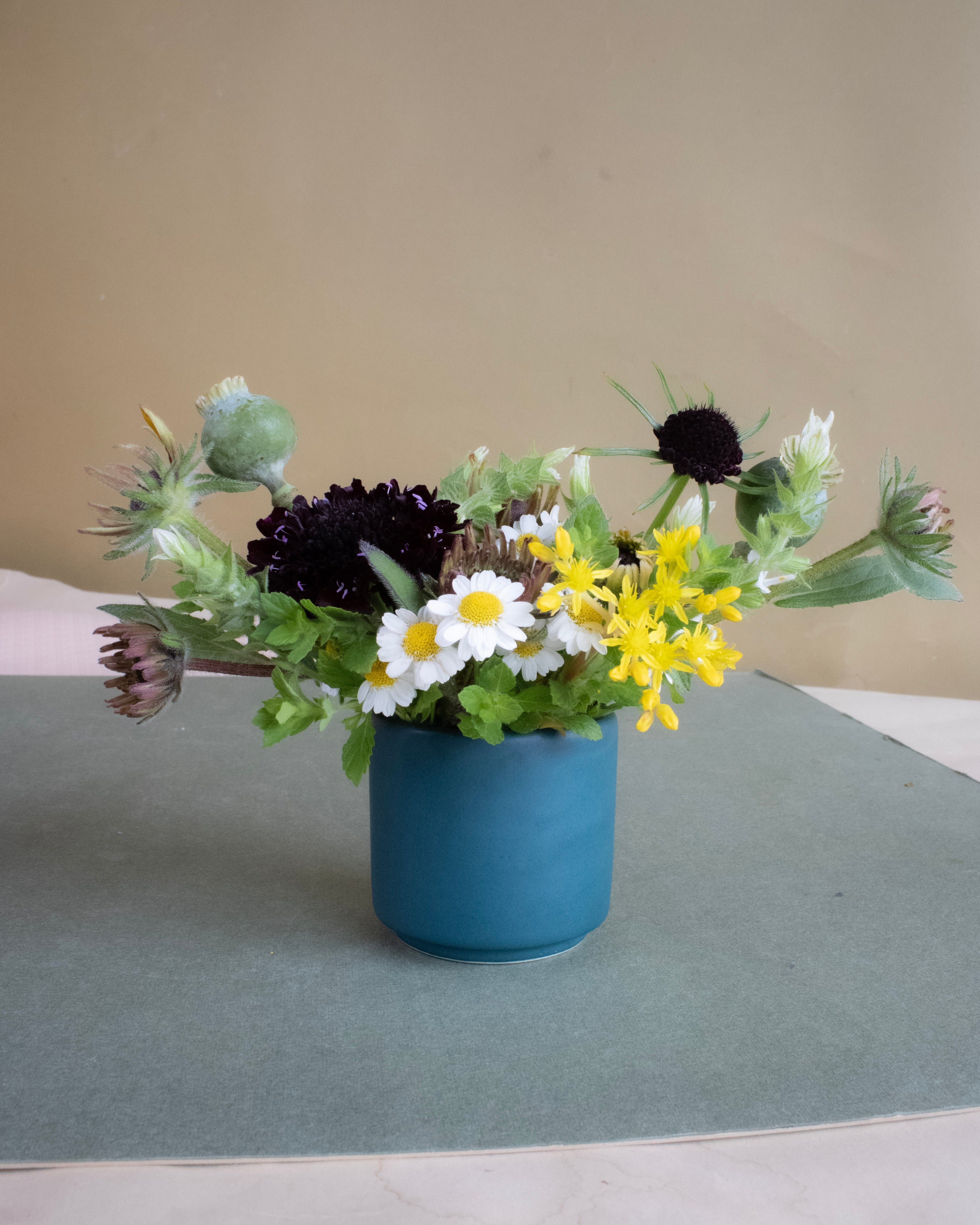 Blue vase with a bouquet of flowers on a gray surface